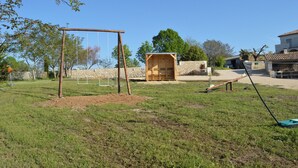 Un espace extérieur verdoyant avec une balançoire, une cabane en bois et un jeu de bascule.