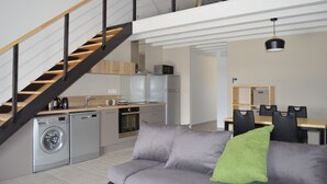 Un appartement moderne comprenant une cuisine, un coin repas et un escalier menant à un niveau supérieur.