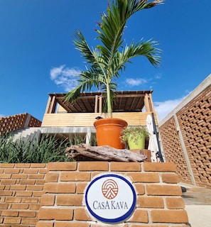 Experience the perfect blend of rustic and modern design at Casa Kava, featuring a charming wooden pergola and a prominent brick wall.