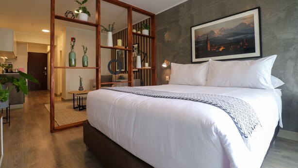 Un dormitorio moderno con una cama grande, un armario de madera y un cuadro de la ciudad en la pared.