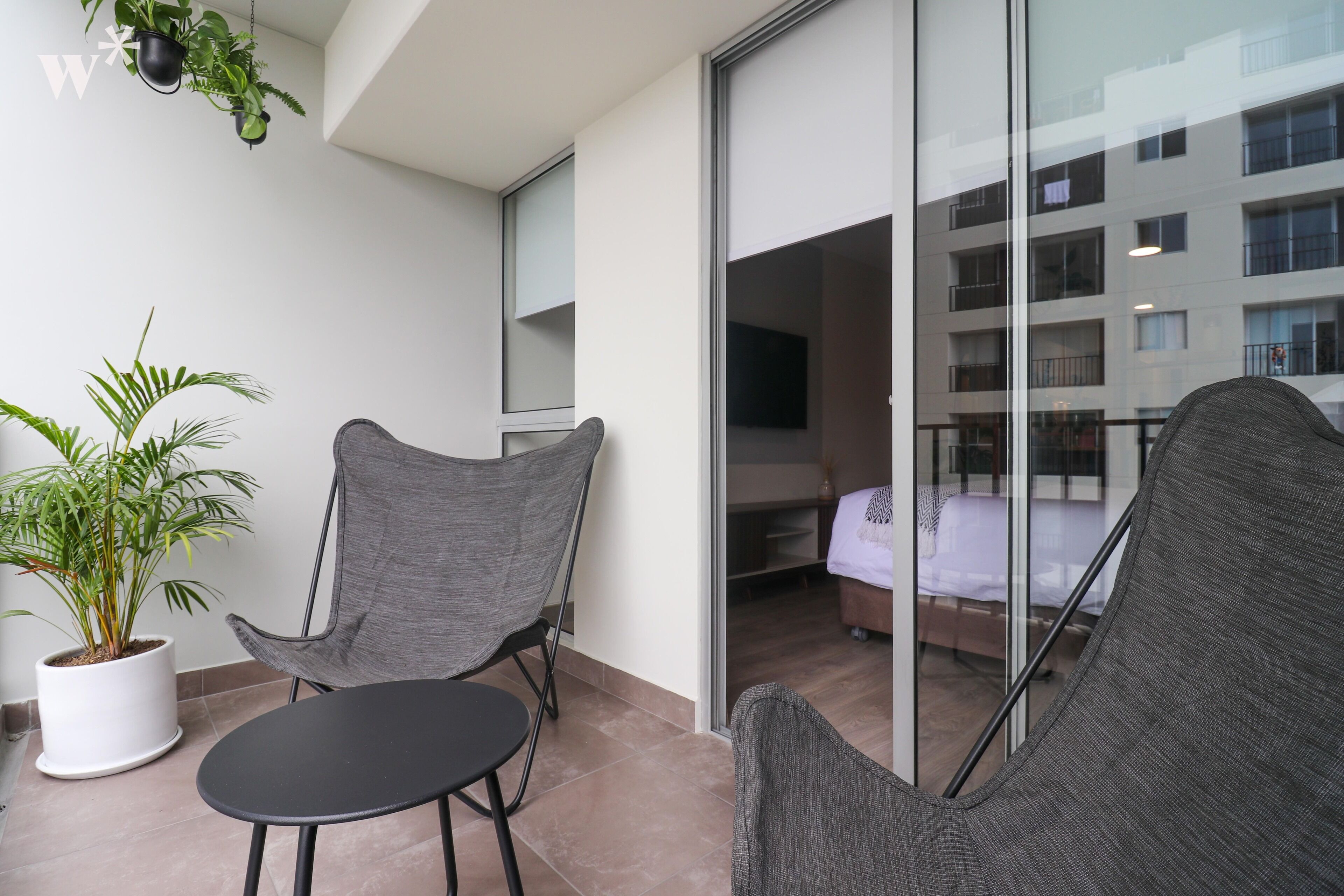 A balcony with two chairs, a small table, and a potted plant.