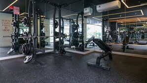 Un gimnasio moderno con equipos de levantamiento de pesas, paredes espejadas y frases motivacionales.