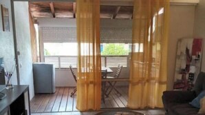 A living room with a tiled floor, a round coffee table, a sofa, and a dining area with a table and chairs. - 1 Bedroom Apartment in Saint-francois (Saint-francois)