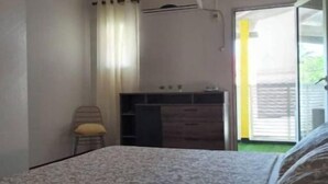 A bedroom with a bed, a chair, a desk, and a sliding glass door leading to an outdoor area. - 1 Bedroom Apartment in Saint-francois (Saint-francois)