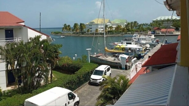 A marina with boats, a white van, and a building with a red roof. - 1 Bedroom Apartment in Saint-francois (Saint-francois)