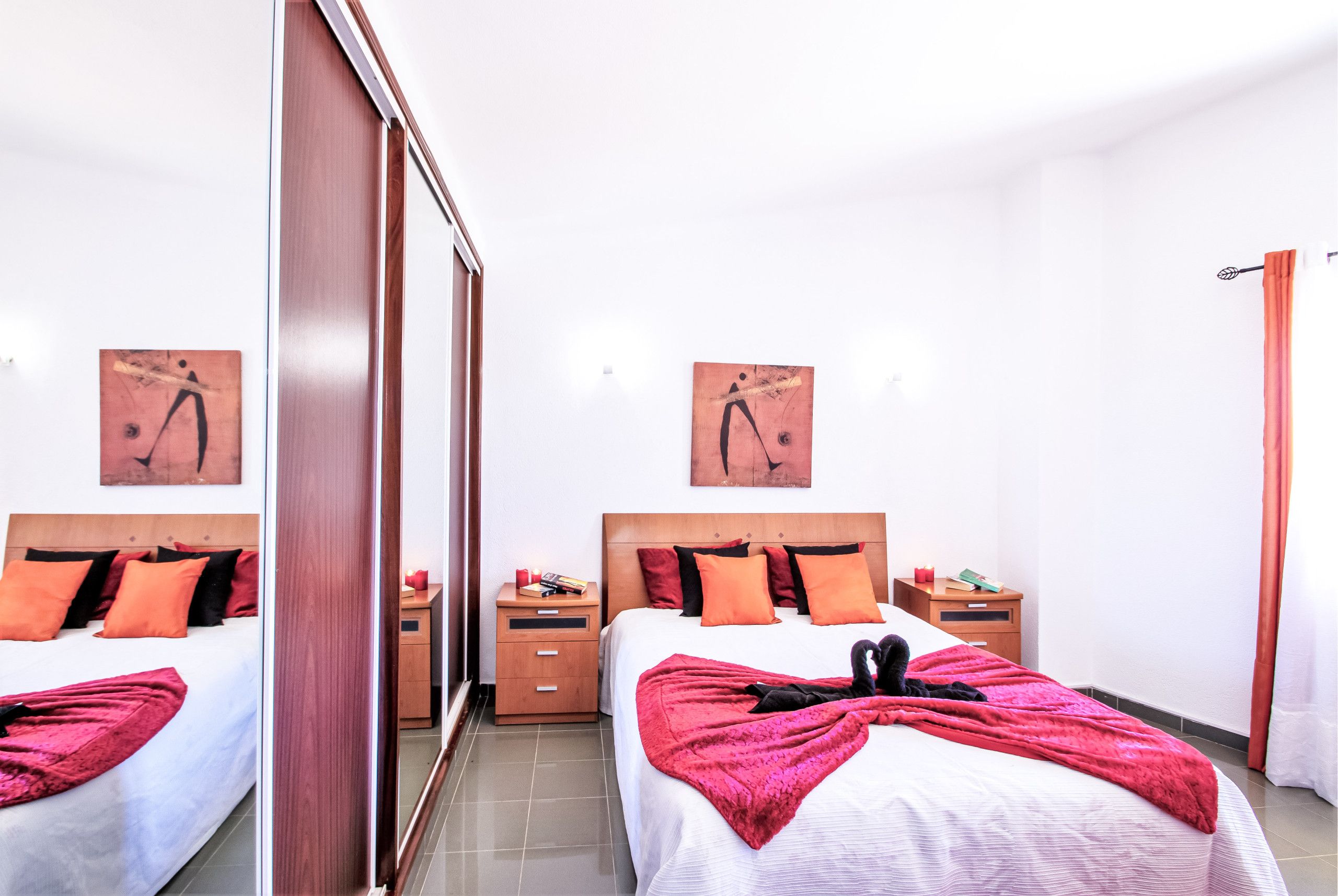 A hotel room with two beds, wooden headboards, and artwork on the walls.