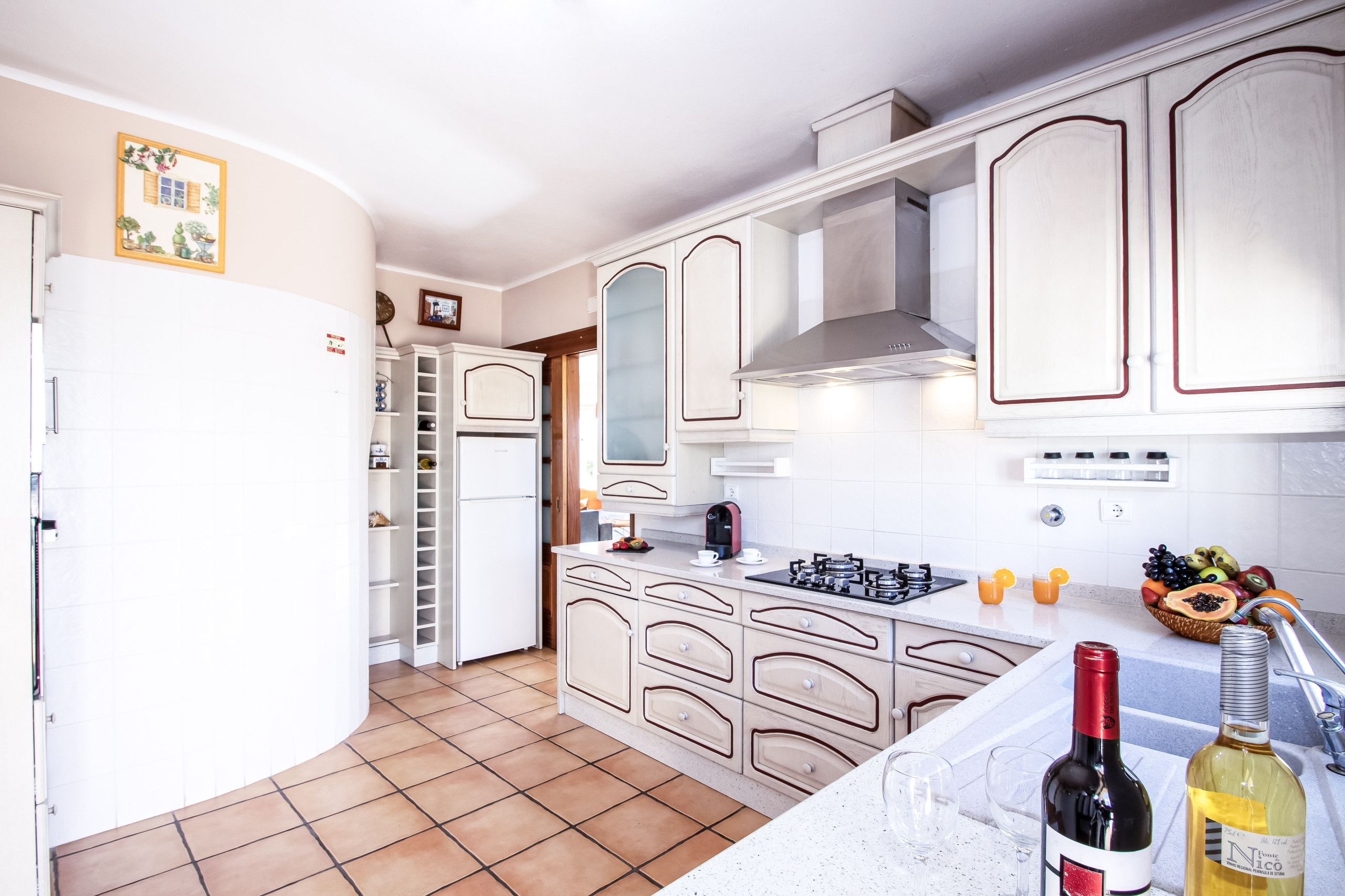 Une cuisine avec des meubles blancs, une cuisinière, un évier et un réfrigérateur.