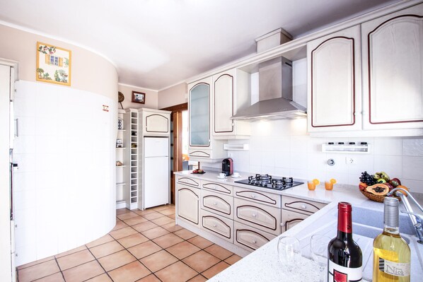 A kitchen with white cabinets, a stove, a sink, and a refrigerator. - Relax villa with BBQ and heatable pool (Carvoeiro)