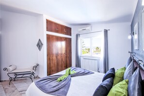 A bedroom with a bed, a wardrobe, a window with curtains, and a radiator. - Relax villa with BBQ and heatable pool (Carvoeiro)