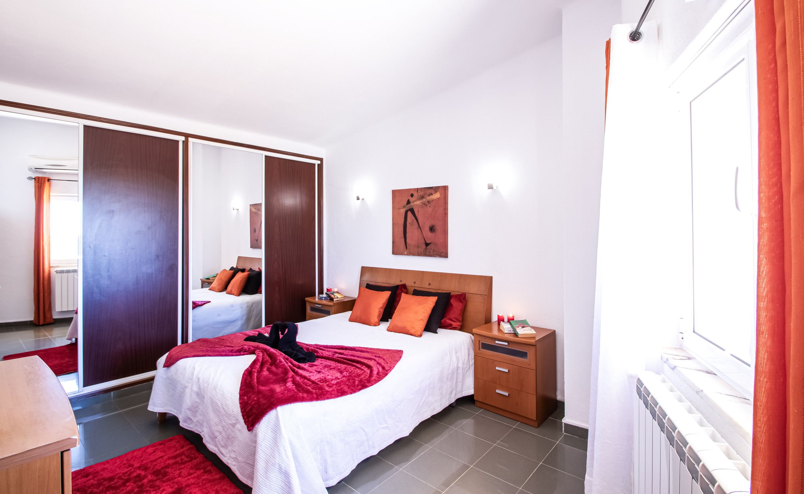 Een hotelkamer met een bed, nachtkastjes, een spiegel en uitzicht.