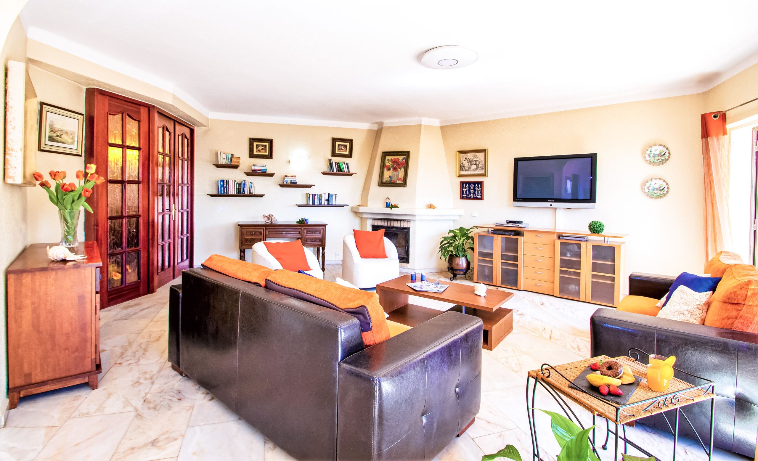 Uma sala de estar com lareira, sofá, televisão e diversos objetos decorativos.