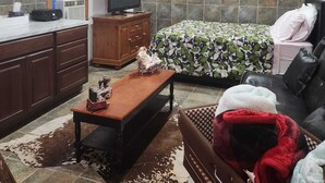A cozy room with a bed, a wooden table, a television, and a ceiling fan.