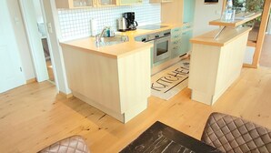 Une cuisine moderne avec des meubles en bois, un îlot central et un tableau noir servant de menu.