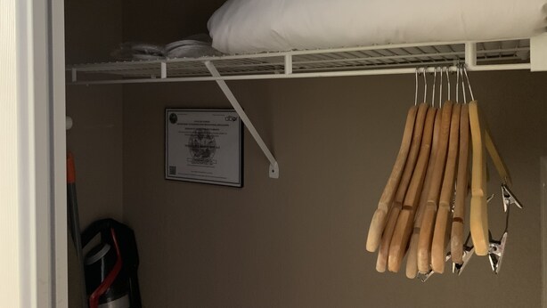 Un lit superposé avec une literie blanche et un certificat encadré accroché au mur.