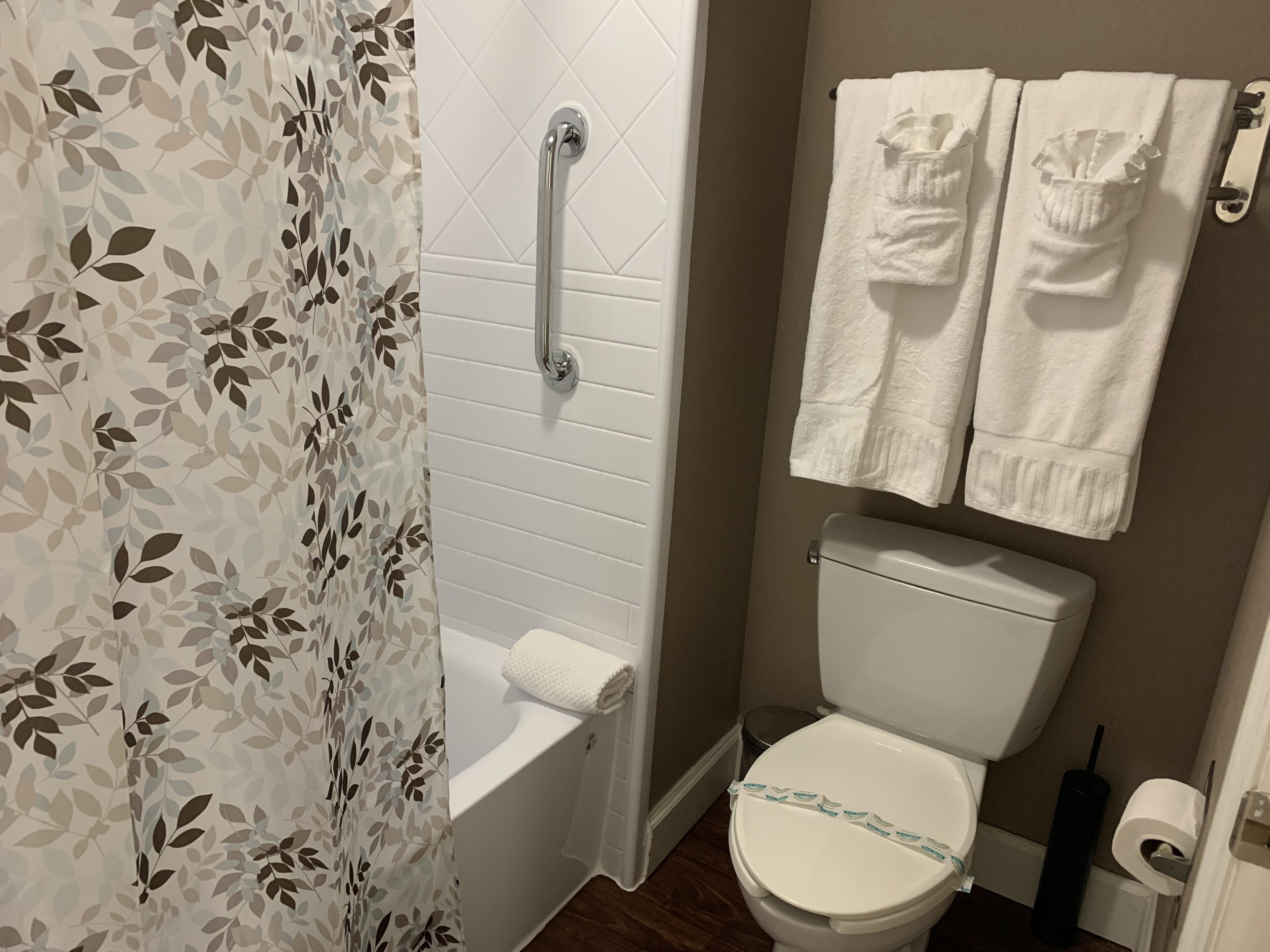 A bathroom with a white toilet, a shower with a glass door, and two white towels hanging on a rack.