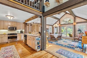 A spacious kitchen with wooden cabinets, stainless steel appliances, and a large island. - Coast and Country Private Estate (Guilford)