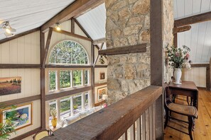A room with a stone wall, wooden beams, a large arched window, and a wooden chair. - Coast and Country Private Estate (Guilford)