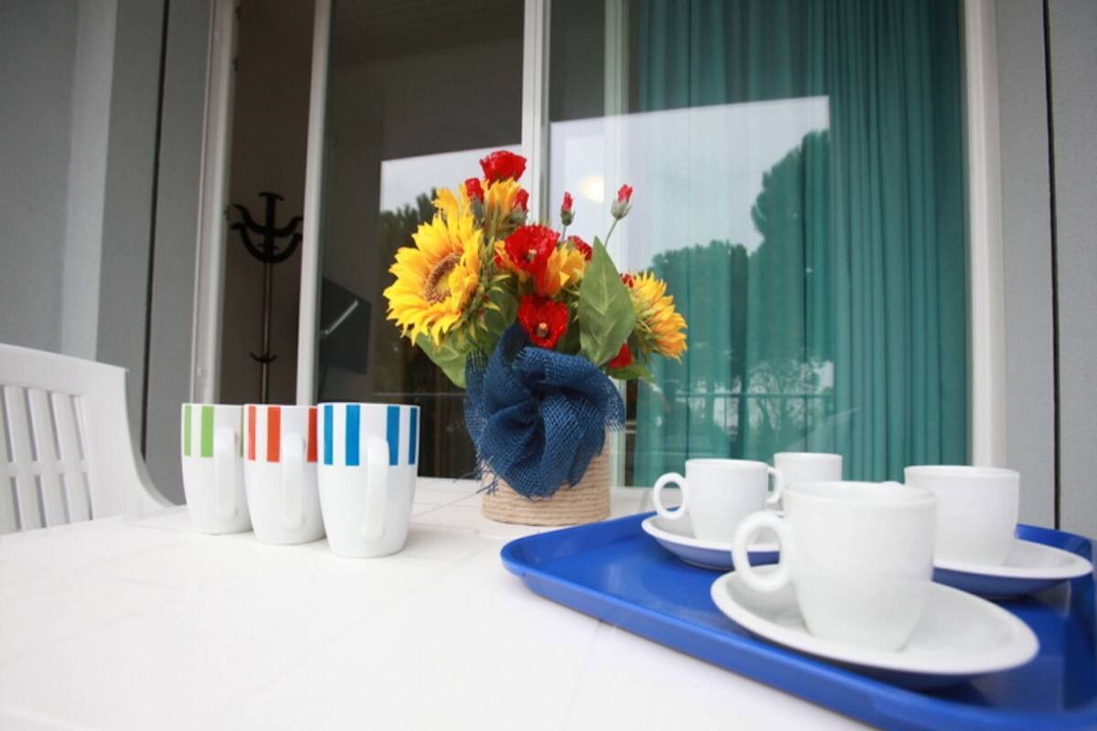 A table with a vase of sunflowers, white cups, and a blue tray.