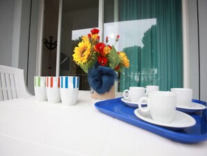 A table with a vase of sunflowers, white cups, and a blue tray. - Beautiful Flat Close to the Beach (Rosolina)