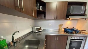 Uma cozinha compacta com uma pia de aço inoxidável, micro-ondas, torradeira e fogão.