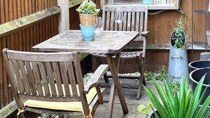 A wooden outdoor seating area with a table and chairs, surrounded by wooden fences and potted plants.