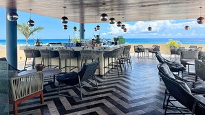 Zona de bar al aire libre con vistas al océano, que incluye una barra, asientos y bolas de discoteca colgantes.