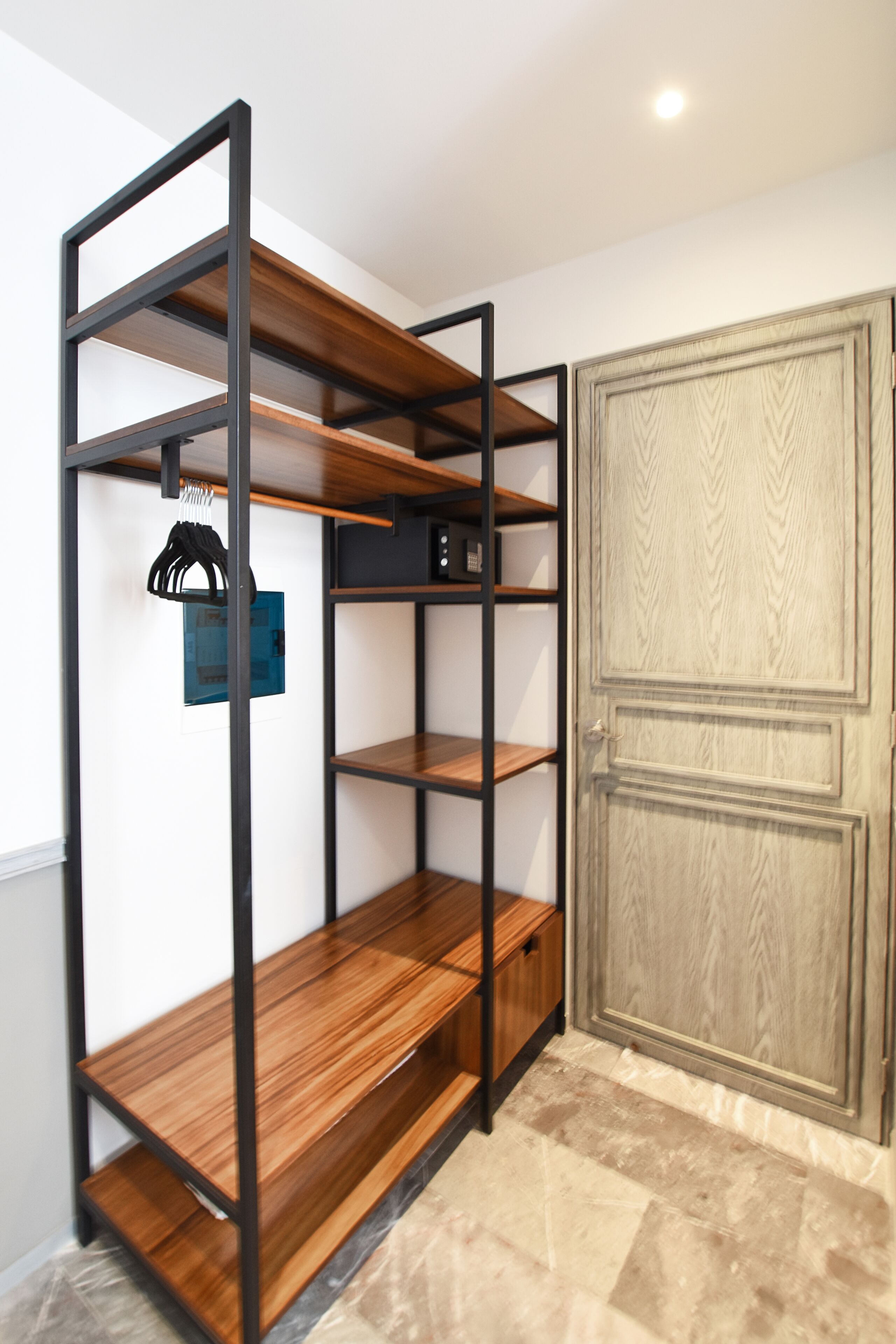 A room with a built-in wooden shelf unit, a door, and a tiled floor.
