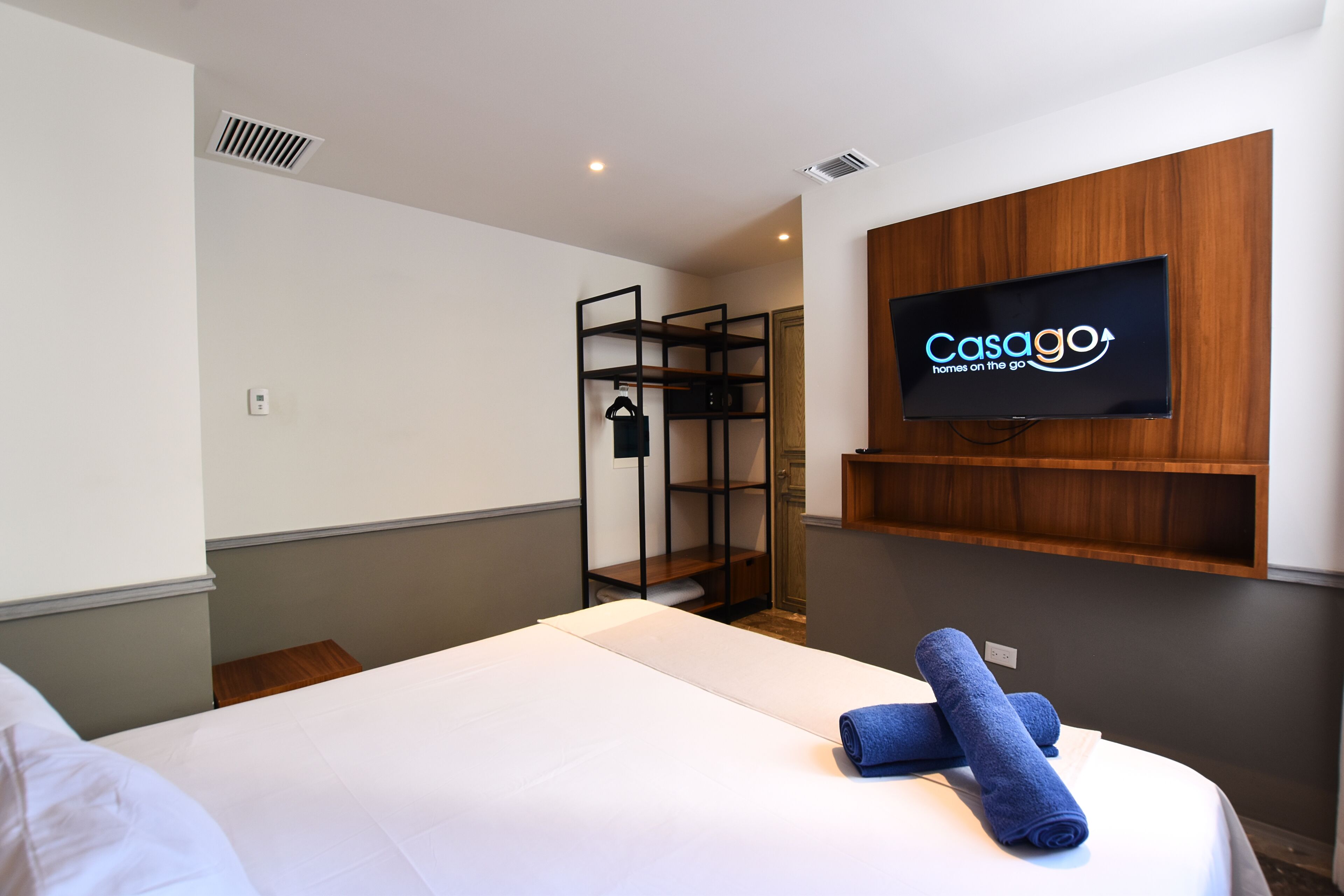Ein Hotelzimmer mit einem Bett, einem an der Wand montierten Fernseher und einem Holzboden darunter.