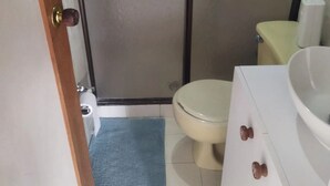 Een compacte badkamer met toilet, wastafel en douche.