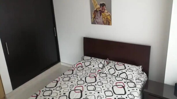 Een slaapkamer met een bed, een donkere kast en een lijst met een afbeelding aan de muur.
