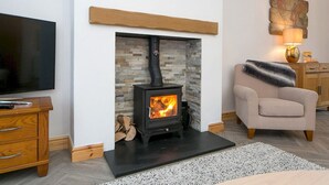 Una sala de estar con chimenea de piedra, televisor y un sillón cómodo.