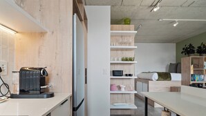 Una cocina moderna con una cafetera espresso integrada, armarios blancos y una pared decorativa de madera.