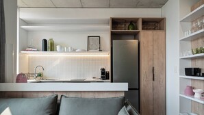 Una cocina moderna con refrigerador empotrado, muebles blancos y una pared de acento de madera.