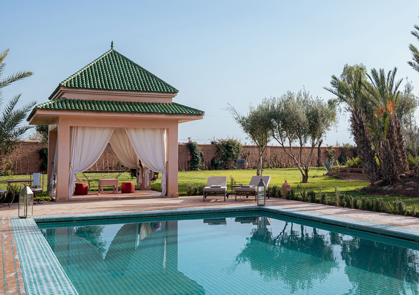 A pool area with a gazebo, lounge chairs, and a clear blue pool.