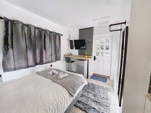 A bedroom with a bed, a desk, a chair, a TV, and a door with a window. - Erin Court Mansion -The Hideaway (South Croydon)