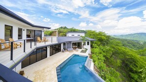 Una moderna casa con piscina, area salotto esterna e vista sul verde circostante.