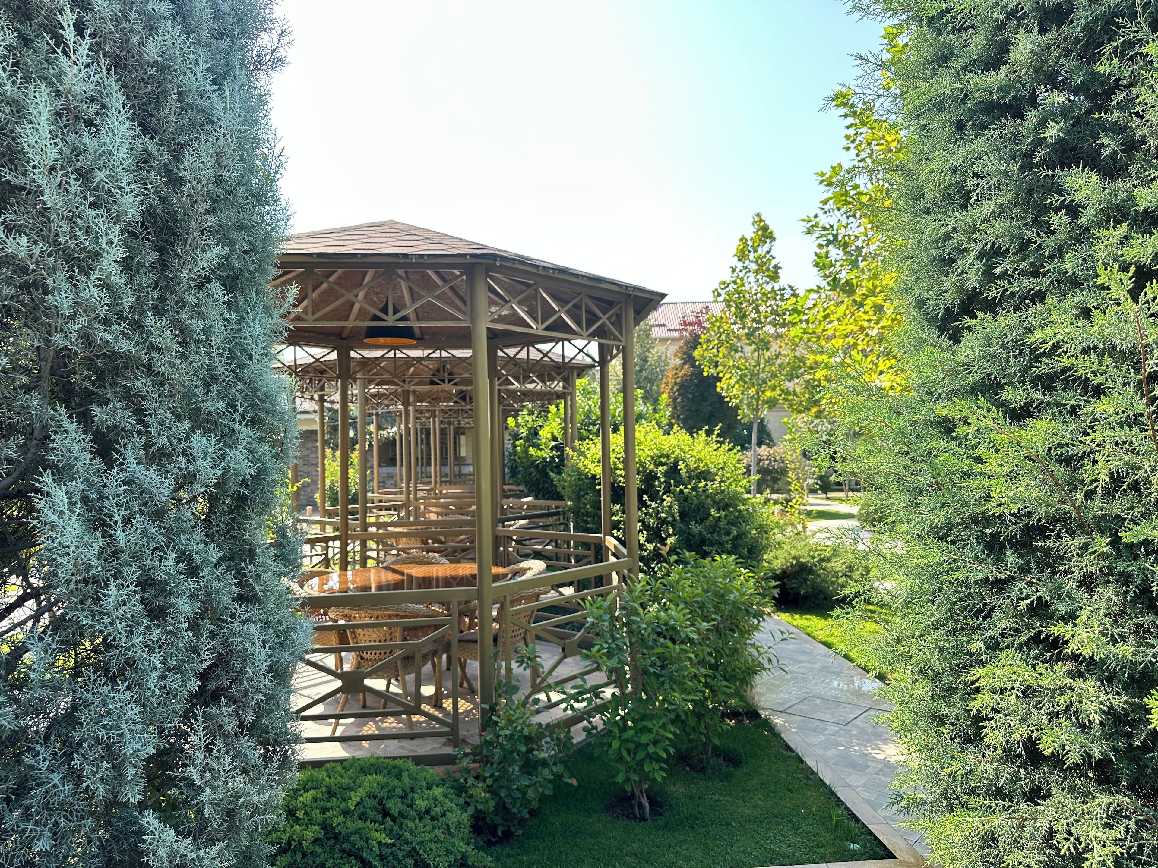 A gazebo with a wooden structure and seating area surrounded by greenery.
