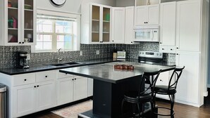 Una cocina moderna con armarios blancos, una isla negra y una campana extractora de acero inoxidable.