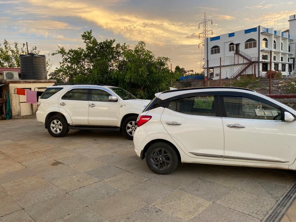 Two white cars parked in a paved area with a building in the background.