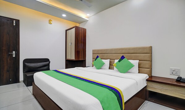 Une chambre d’hôtel avec un lit, un bureau, une chaise et une armoire.