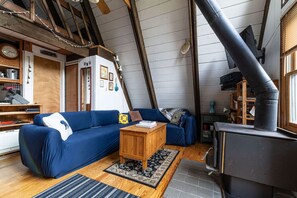Cozy cabin living space with a blue sofa, wooden coffee table, and a stove, offering a warm and inviting atmosphere.