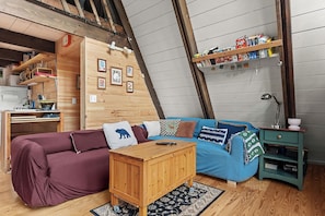 Quarto de sótão acolhedor com uma cama de madeira estilo beliche, uma pequena escrivaninha e uma estante de livros.