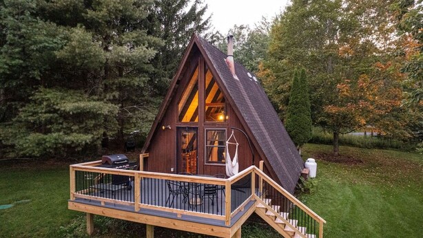 Une cabane en bois dotée d’une terrasse et d’un escalier menant à l’entrée.
