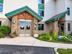 A spa entrance with a stone facade, a green roof, and a flower bed with colorful flowers. -  Modern Mountain Retreat - Ski-in-out - Heated Pool and Hot Tub (Steamboat Springs)