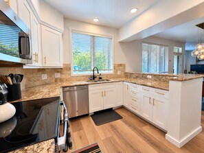 A modern kitchen with white cabinetry, a stainless steel dishwasher, and a granite countertop. -  Modern Mountain Retreat - Ski-in-out - Heated Pool and Hot Tub (Steamboat Springs)