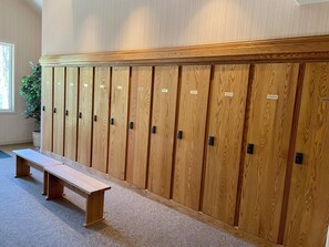 A row of wooden lockers with name tags, a bench, and a potted plant in a room with a carpeted floor and a window. -  Modern Mountain Retreat - Ski-in-out - Heated Pool and Hot Tub (Steamboat Springs)