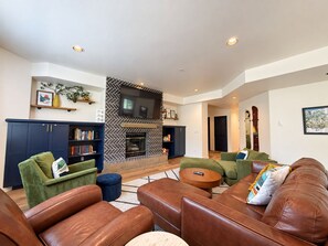 A modern living room with a fireplace, leather sofas, and a bookshelf.