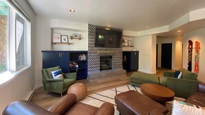 A modern living room with leather sofas, a fireplace, and a television mounted on the wall. -  Modern Mountain Retreat - Ski-in-out - Heated Pool and Hot Tub (Steamboat Springs)