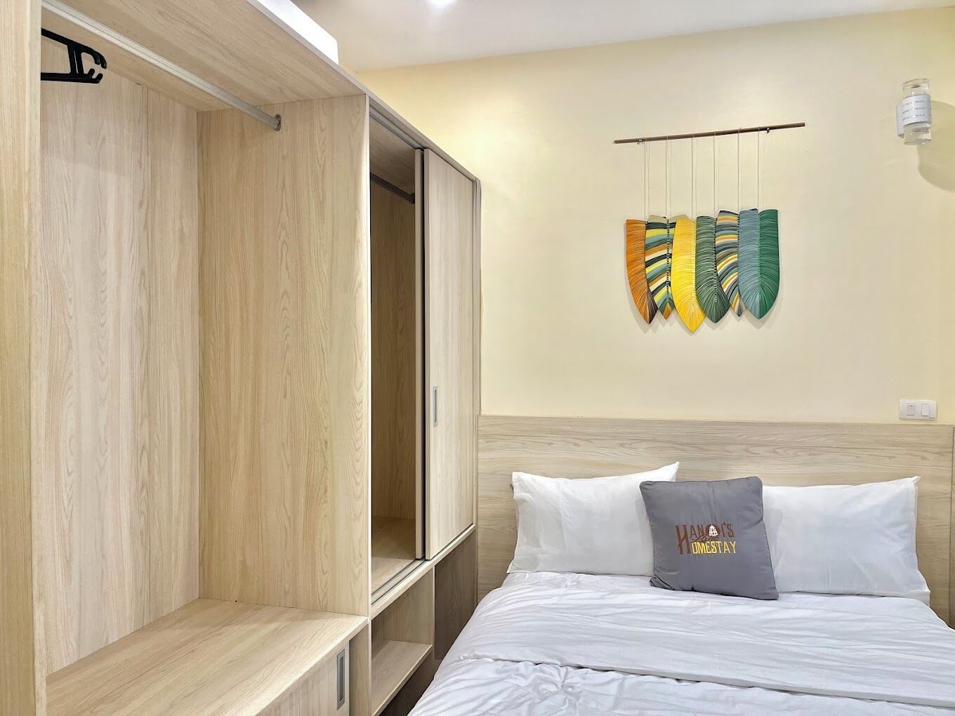 Una camera d'albergo con un letto, un armadio e uno scaffale a parete con oggetti decorativi.