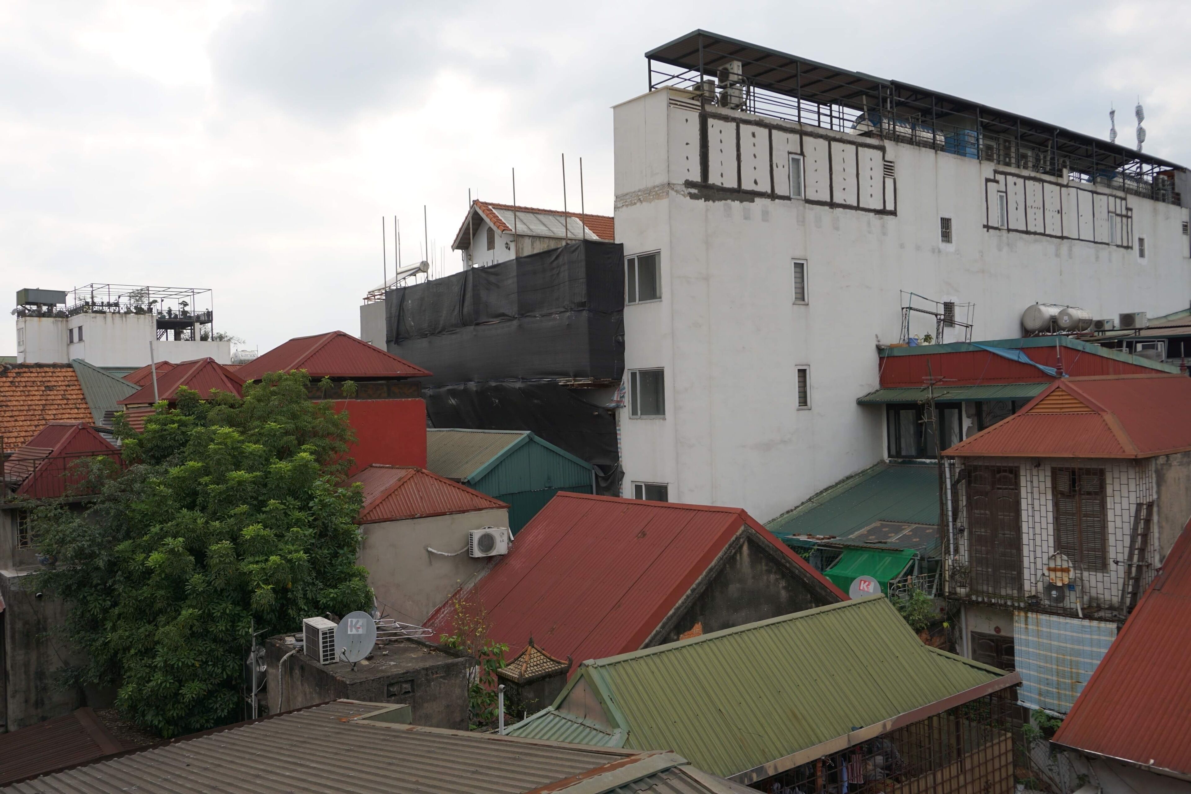 A residential area with multiple buildings, some with red and green roofs, and a large white building with a black section on the side.